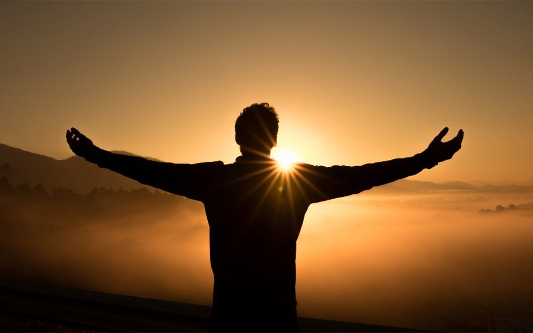 Persona con los brazos abiertos hacia el sol