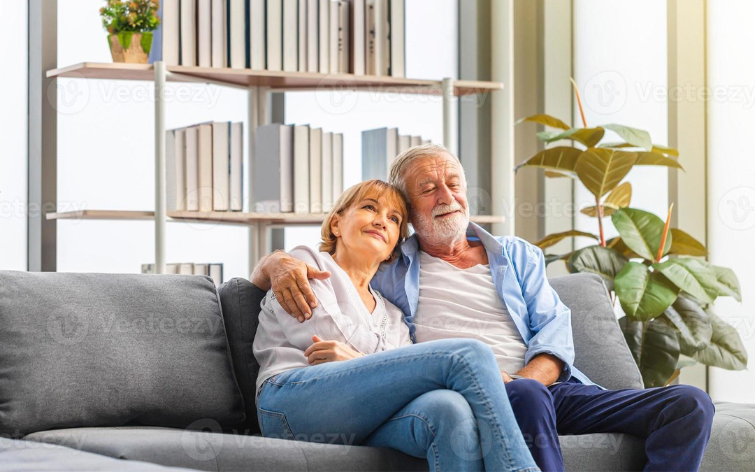 Pareja mayor abrazada sentada en un sofá