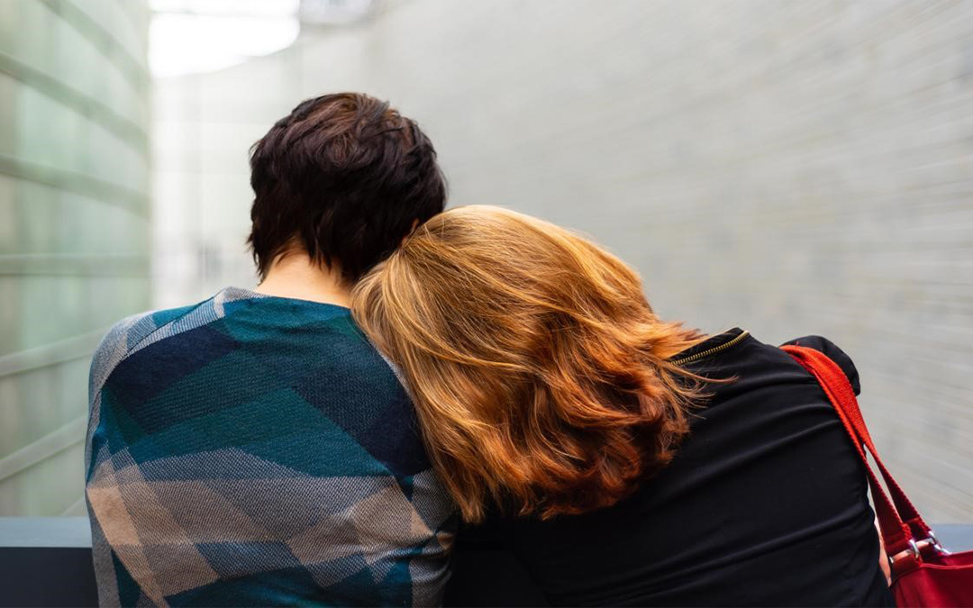 Pareja sentada con las cabezas tumbadas una sobre la otra