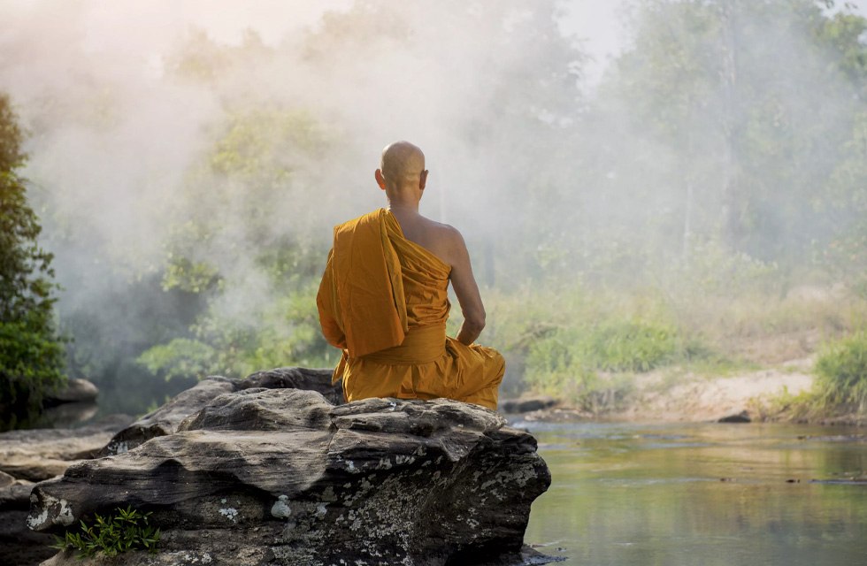 Persona budista meditando delante de un río