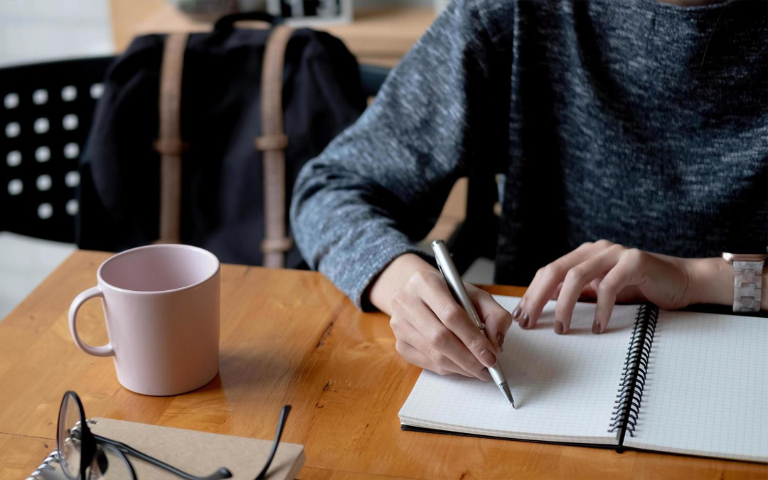 Persona apuntando tareas en un caderno