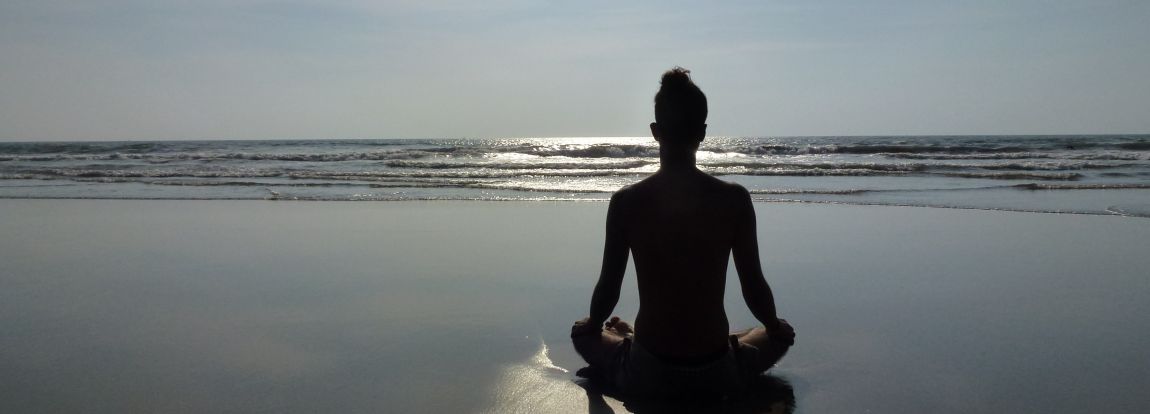 Persona meditando junto al mar